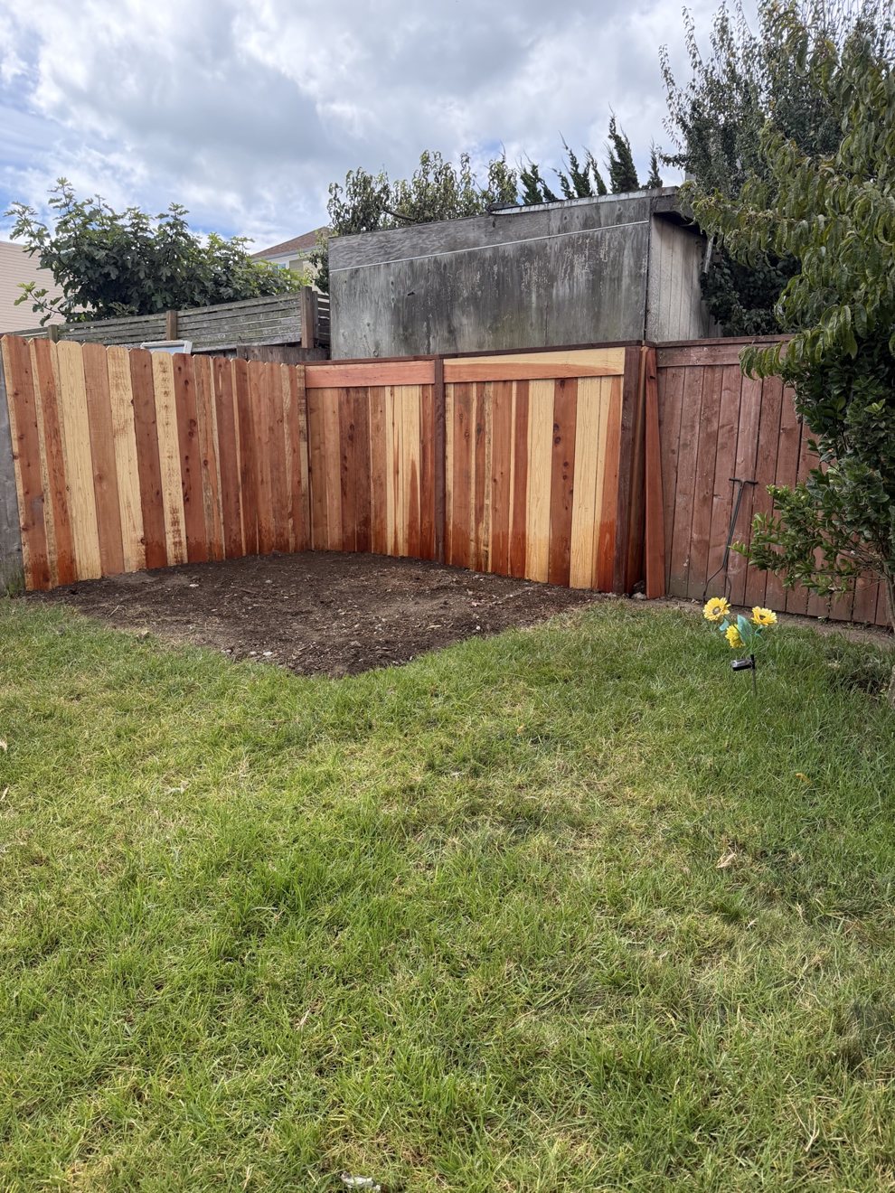 New redwood fence corner section in a grassy backyard