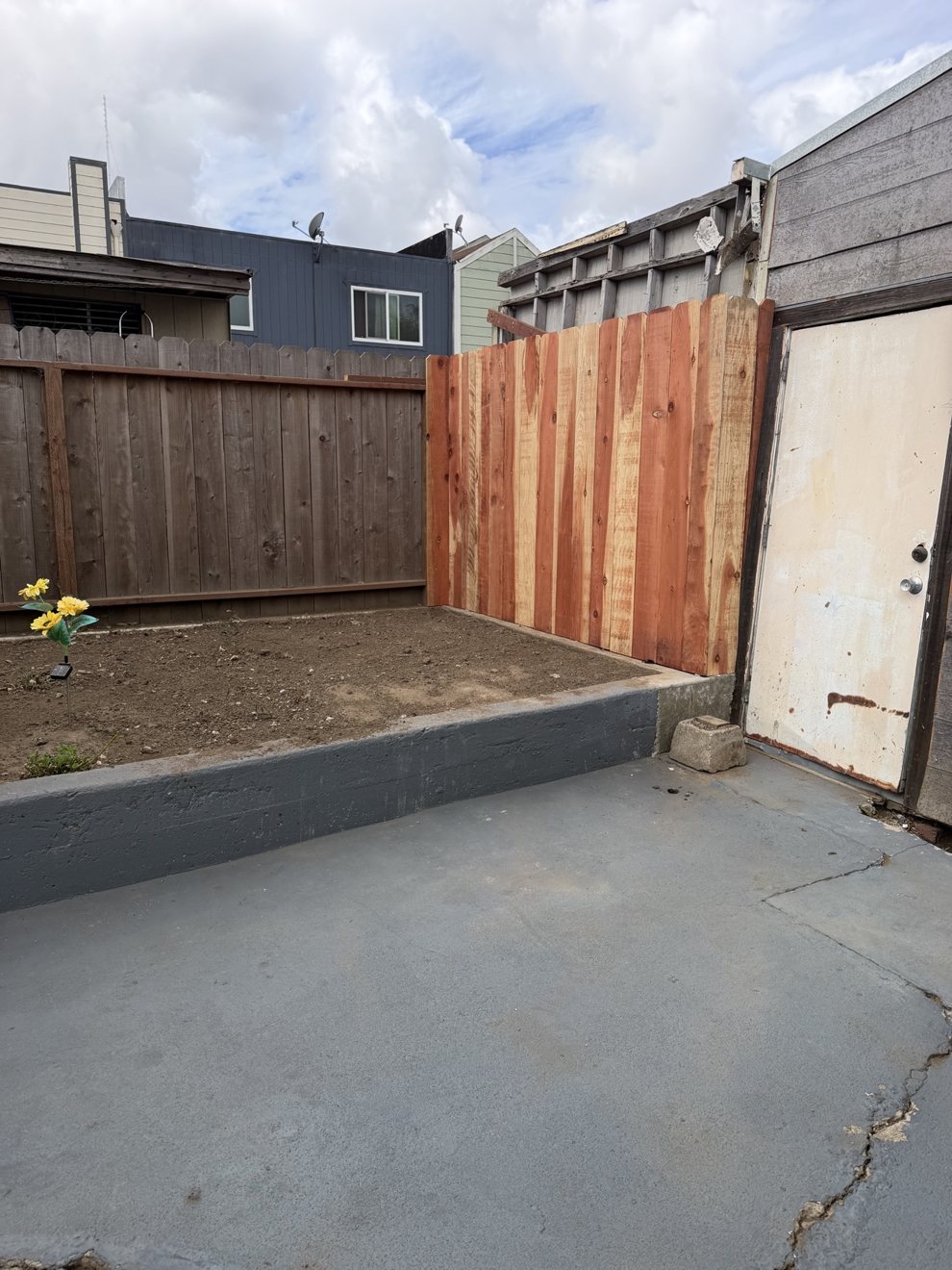New redwood fence section alongside a concrete patio