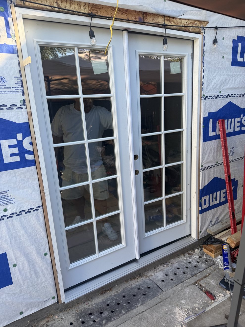 New white French doors installed on a backyard shed